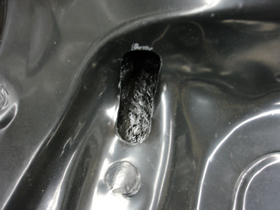 Close-up of a black carbon fiber piece inserted into a gray molded plastic area with some circular indentations