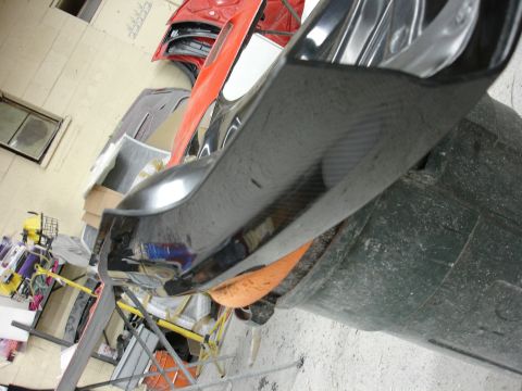 1993 Ford Taurus - A close-up view of a carbon fiber automotive part, likely a body panel, in a workshop setting.