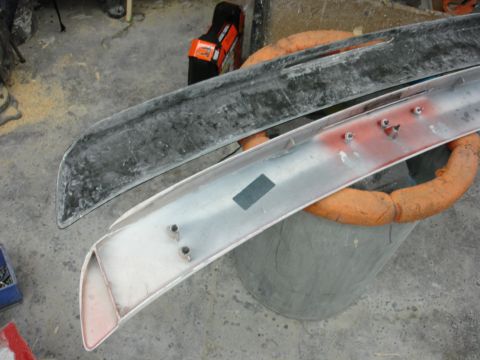 1993 Ford Taurus - Two car spoilers, one black and one silver, are shown in a workshop setting.