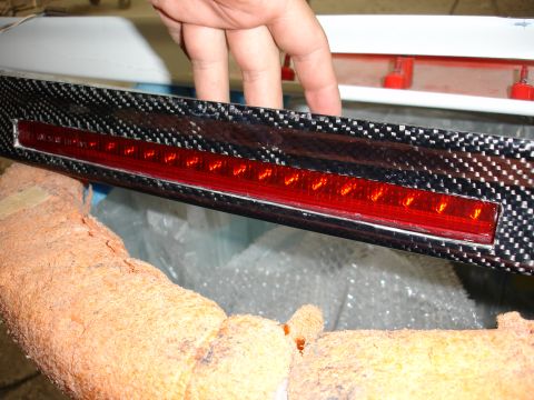 1993 Ford Taurus - A custom carbon fiber third brake light assembly with red LEDs is being held.