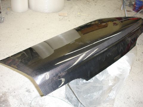 1993 Ford Taurus - A custom carbon fiber car part, likely a hood or trunk lid, is shown in a workshop setting.