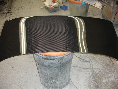 1993 Ford Taurus - Carbon fiber hood on a bucket in a workshop.