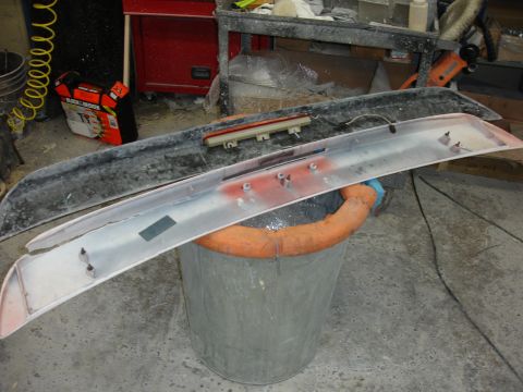 1993 Ford Taurus - A disassembled car spoiler rests on a bucket, revealing its internal structure and wiring for the brake light.