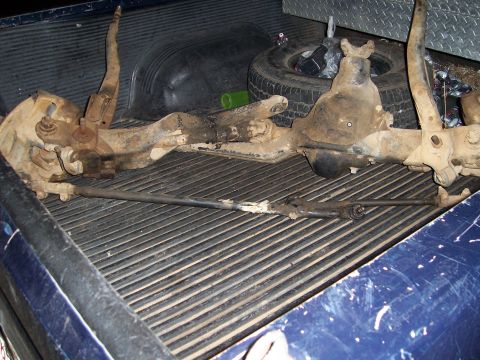 1983 Ford Bronco - A disassembled front axle assembly rests in the bed of a pickup truck.