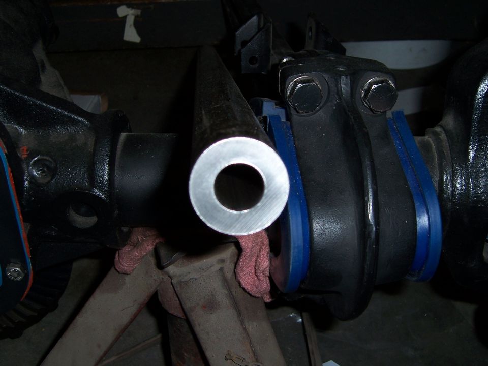 Close-up of a metal rod end with a hole, connected to black steering components with blue bushings