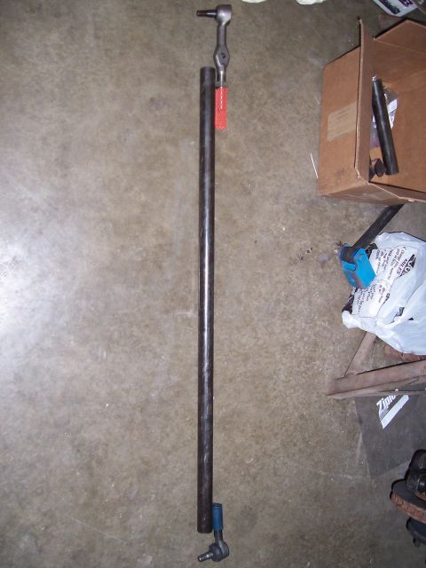 1983 Ford Bronco - A steering linkage part is shown with a ratchet tool, against a concrete background.