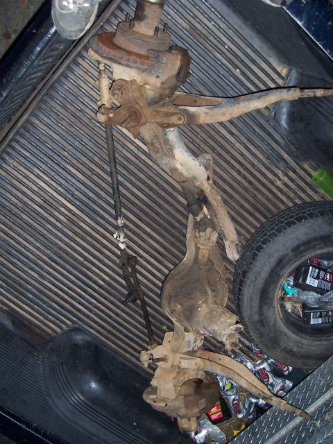 1983 Ford Bronco - A disassembled solid axle suspension component is visible in the bed of a pickup truck.