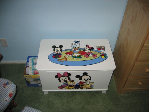 2002 Ford Taurus - A white wooden toy chest painted with baby Disney cartoon characters on the lid and front panel, sitting on green carpet in a nursery besid…