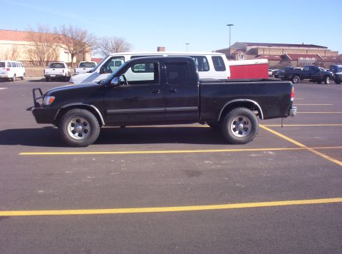 2003 Toyota Tundra - Side view of a black 2003 Toyota Tundra pickup truck with a brush guard in a parking lot.
