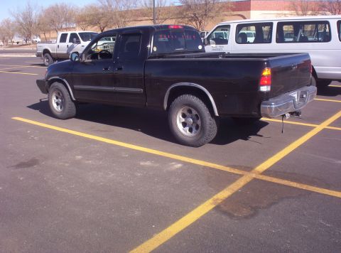 2003 Toyota Tundra - A black pickup truck is parked in a lot with yellow lines. Other vehicles are in the background.