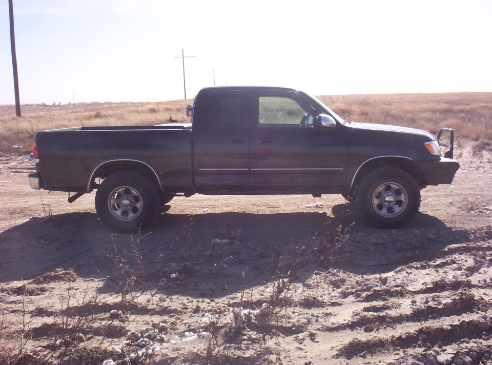 Dark pickup truck parked on dirt road. It has a single cab and a long bed