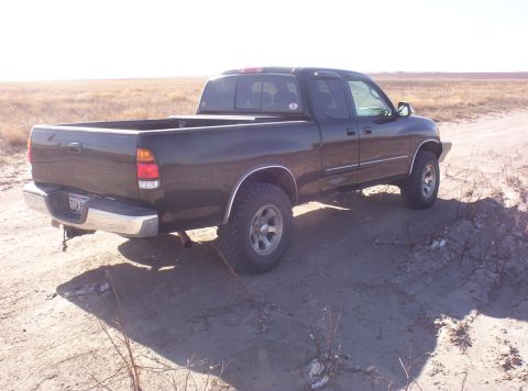 2003 Toyota Tundra - A dark green 2003 Toyota Tundra pickup truck is seen from the rear three-quarter angle on a dirt road.