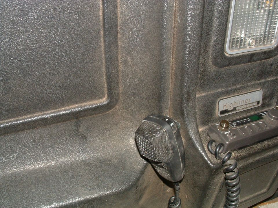 CB microphone resting on textured cab panel near a dome light and Highliner badge