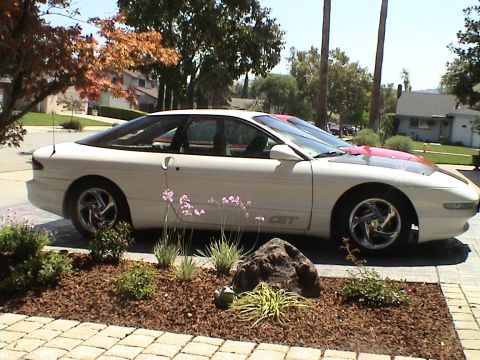 1997 Ford Probe - A white 1997 Ford Probe GT is parked in front of a house, with another vehicle visible behind it.