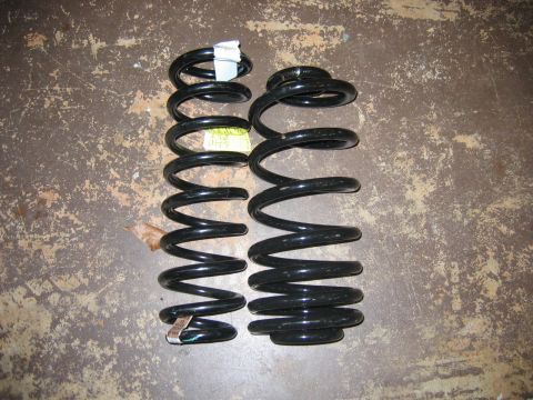 1985 Ford LTD Crown Victoria - Two black coil springs, likely for a vehicle's suspension system, are shown on a concrete surface.