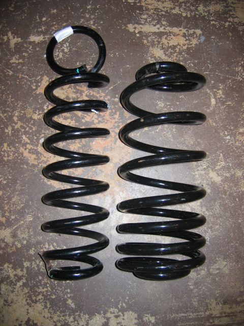 1985 Ford LTD Crown Victoria - Two automotive coil springs are shown, likely for suspension replacement. One spring is noticeably smaller than the other.