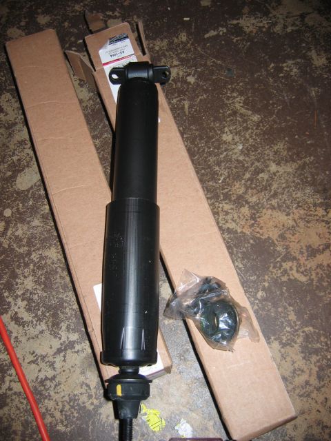 1985 Ford LTD Crown Victoria - A black shock absorber is shown with its packaging and hardware, lying on a concrete surface.