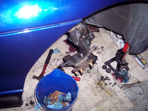 1995 Ford Probe - Car suspension parts are laid out on the floor, with tools and a blue bucket nearby.
