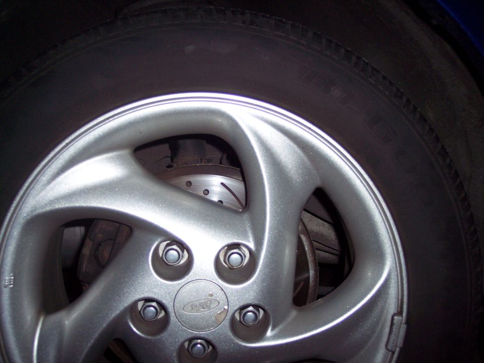 Close-up of a silver alloy wheel with a Ford logo in the center, showing a brake rotor behind it