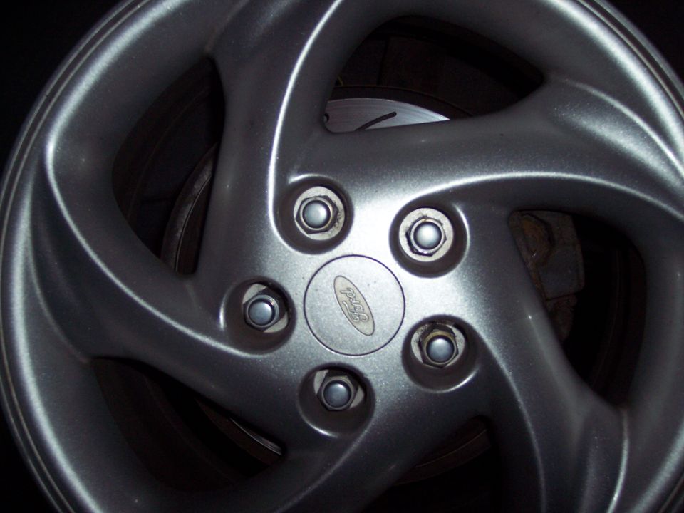 Silver five-spoke Ford wheel with a visible Ford logo and brake rotor