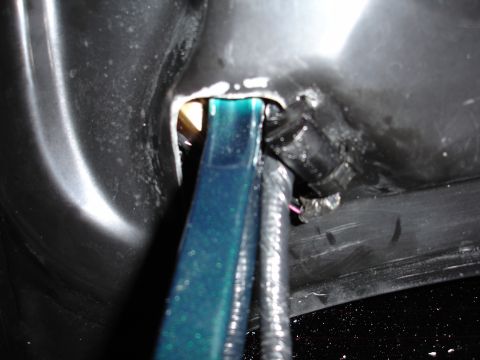 1993 Ford Taurus - A close-up view shows a blue conduit and a wiring harness secured within a dark, possibly plastic, automotive component.