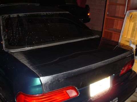 1993 Ford Taurus - Rear view of a car trunk a carbon fiber wrap and a wet rear window.