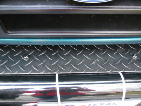 1996 Ford Bronco - Close-up of a vehicle's front bumper a diamond plate insert and chrome detailing.