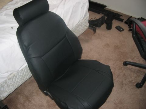 1991 Ford Bronco - A black car seat is shown, detached from a vehicle and placed on a carpeted floor.