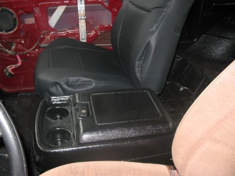 1991 Ford Bronco - The interior of a vehicle shows a newly installed black seat and center console, with the door panel removed.
