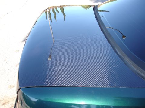 1993 Ford Taurus - A car's hood and windshield are covered in carbon fiber, reflecting the surrounding environment.
