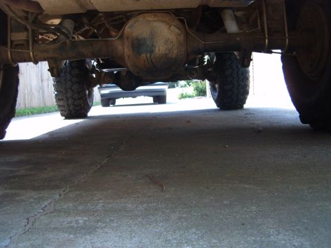 1988 Ford Bronco - The underside of a vehicle is captured, revealing its robust suspension and large off-road tires, with a second vehicle faintly visible ahe…