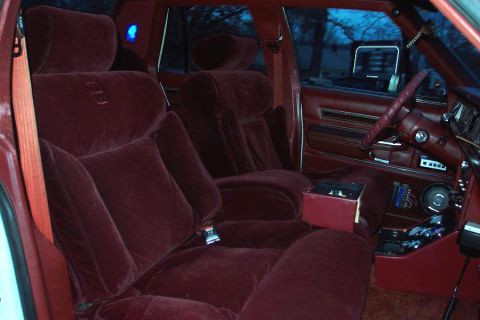 1985 Ford LTD Crown Victoria - The plush interior features maroon velour seats and matching door panels, with a glimpse of the dashboard and steering wheel.