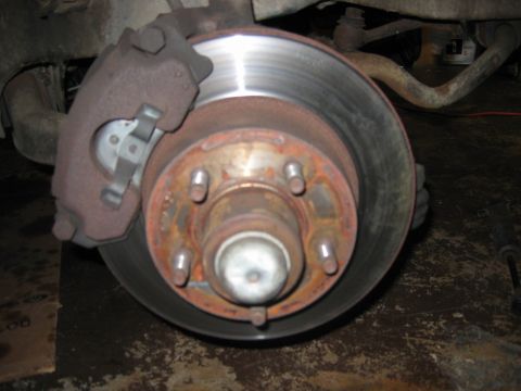 1985 Ford LTD Crown Victoria - Close-up of a vehicle's front brake rotor and caliper assembly, showing signs of wear and rust.