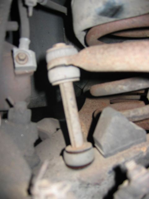 1985 Ford LTD Crown Victoria - This photo shows a close-up view of a vehicle's suspension system, specifically a sway bar end link and coil spring.