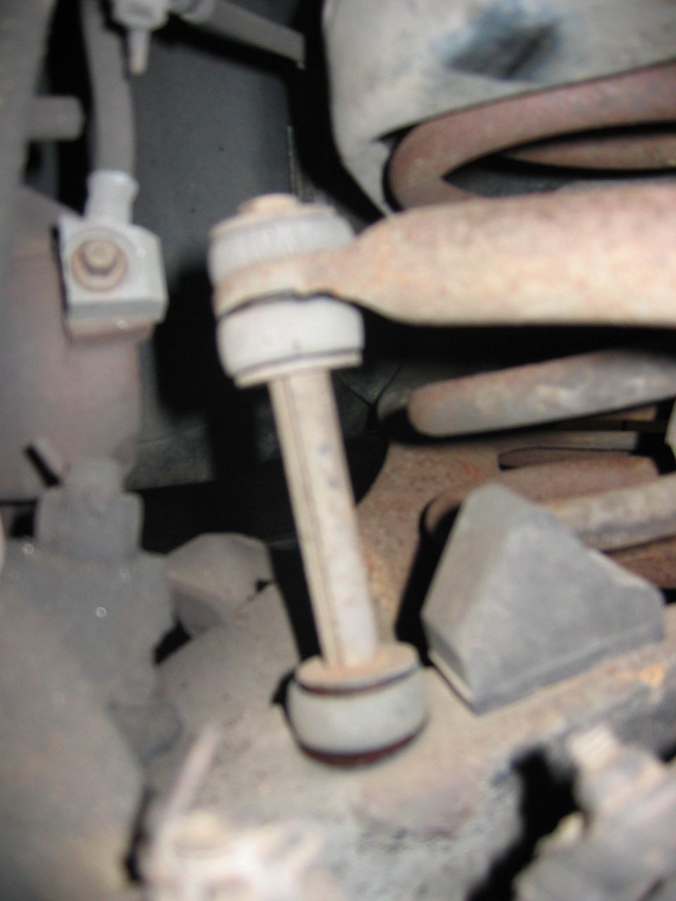 Close-up of a car's sway bar end link and coil spring