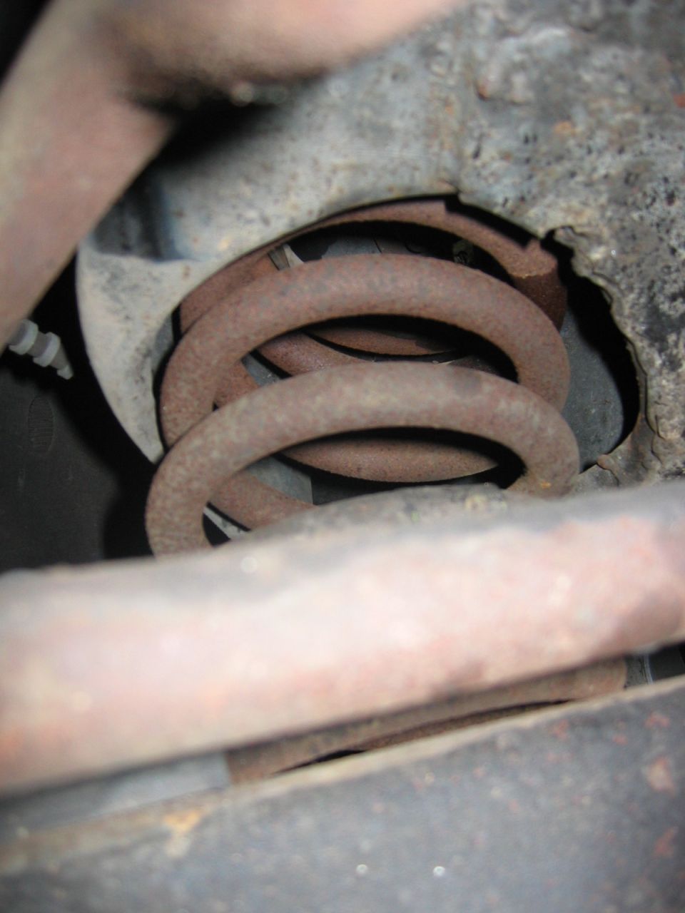Rusted coil spring and suspension parts, close-up view