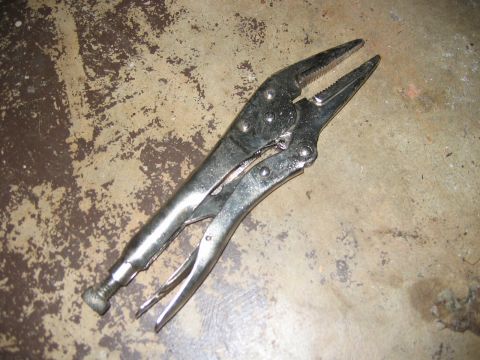 1985 Ford LTD Crown Victoria - A pair of metal locking pliers rests on a worn, discolored concrete surface.