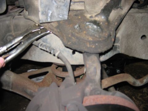 1985 Ford LTD Crown Victoria - A mechanic uses vise grips on a suspension part, likely during a brake or suspension repair.
