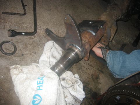 1989 Ford Bronco - A person works on a vehicle's axle assembly, with tools and a towel nearby on the garage floor.
