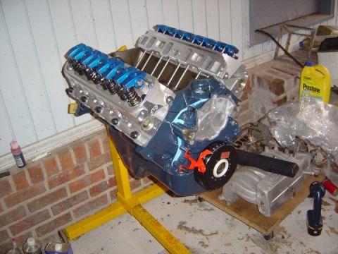 1986 Ford Bronco - A blue V8 engine is mounted on a yellow stand, ready for installation or work.