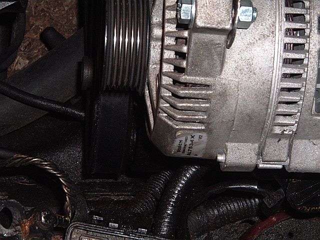 Close-up of an alternator and serpentine belt pulley with Bosch label in an engine bay