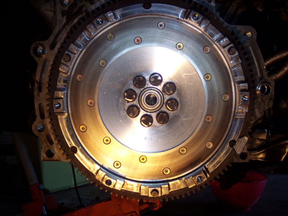 Close-up of a flywheel with a starter ring gear, bolted to an engine block