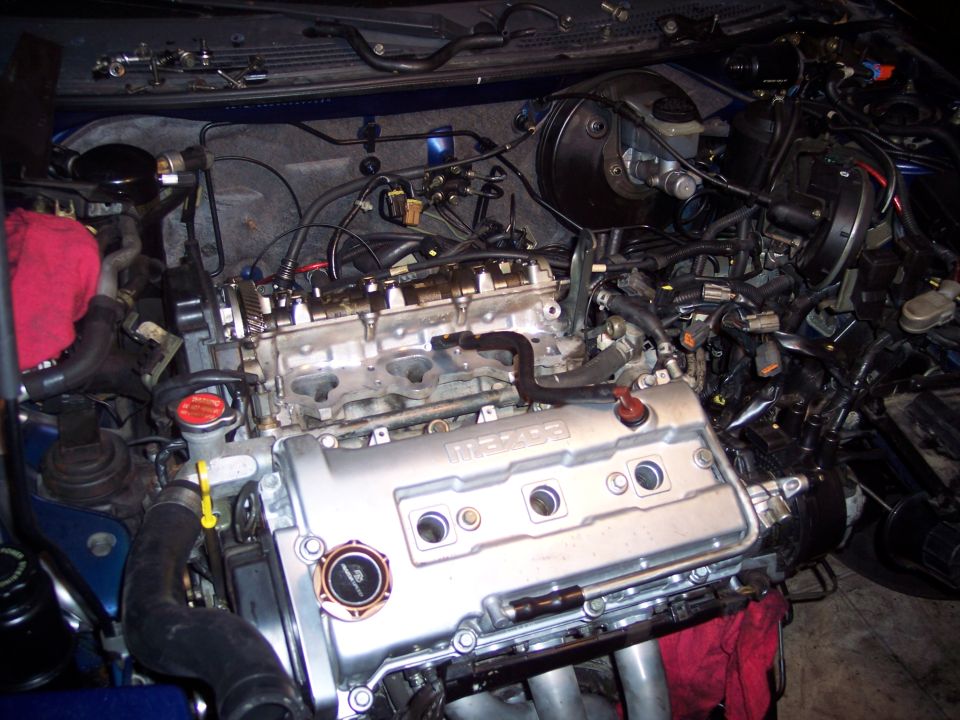 Engine bay with a Mazda engine, wires and hoses visible