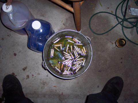 1995 Ford Probe - A bucket filled with cigarette butts soaking in a greenish liquid, next to two large plastic jugs and a wooden chair leg.