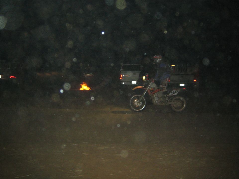 Dirt bike racer numbered 426 riding past a pickup truck at night