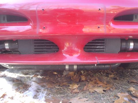 1995 Ford Probe - Close-up of a red car's front bumper, revealing an aftermarket intercooler and piping.