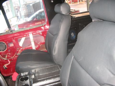 1991 Ford Bronco - View of the interior, showing the driver's side door panel with exposed wiring and a black seat.