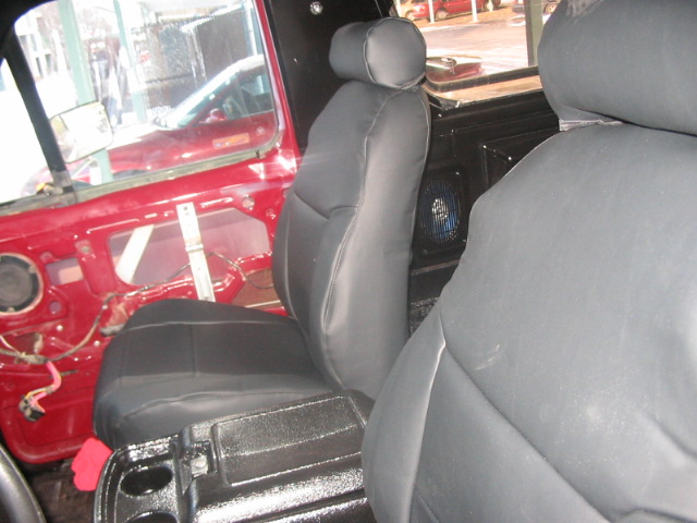 Interior view of vehicle with exposed red door panel and black seats