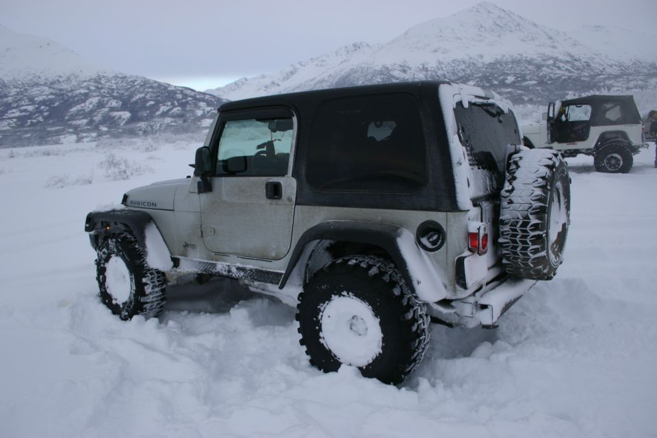 White 2003 Jeep TJ Rubicon stuck in deep snow, another Jeep visible in background