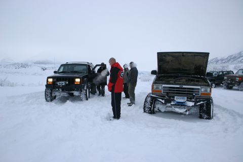 2003 Jeep TJ - A group of people and their vehicles are stopped in a snowy landscape, with one vehicle's hood open.